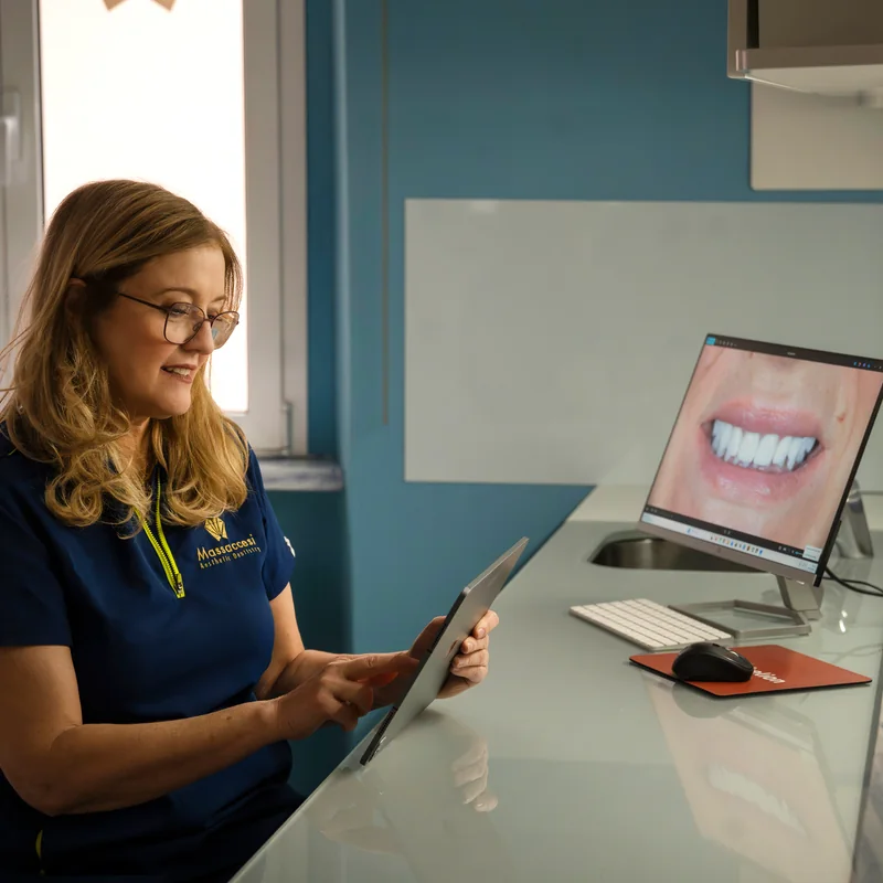Consultazione di una fotografia del sorriso sul tablet, accanto al monitor in studio.