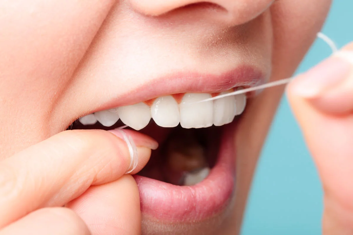 Uso del filo interdentale per la pulizia quotidiana degli spazi tra i denti.